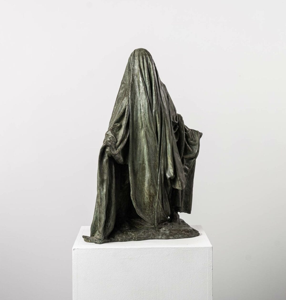 La sculpture en bronze "Ombre voilée II" de Guy Le Perse représente un personnage voilé les bras ouverts. Cette pièce s'inspire des hypocrites de la Divine Comédie de Dante.