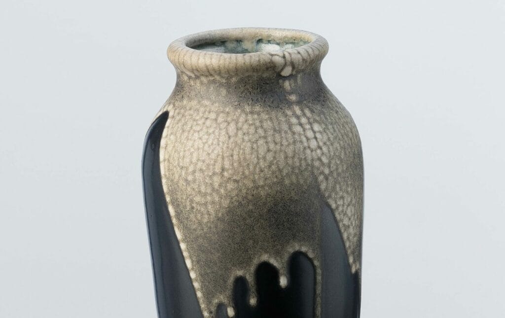 An ovoid stoneware vase by Léon Pointu, a master ceramist from the Carriès school, made in Saint-Amand-en-Puisaye. The black enamelled base is topped by a beige glaze with a snakeskin motif covering the upper part. The base bears a number and the signature of Pointu.