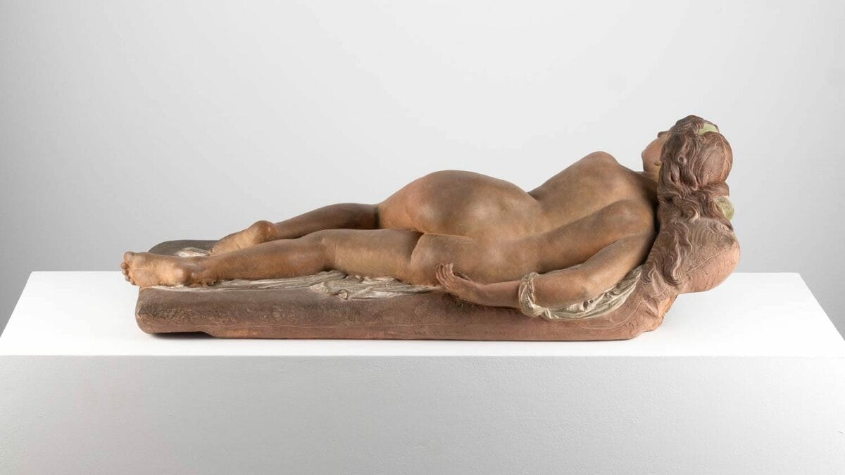 Polychrome terracotta figure of a nude woman reclined on a couch. This artwork, named "The Vanity," was crafted and painted by Joseph Félon for the 1866 Salon.