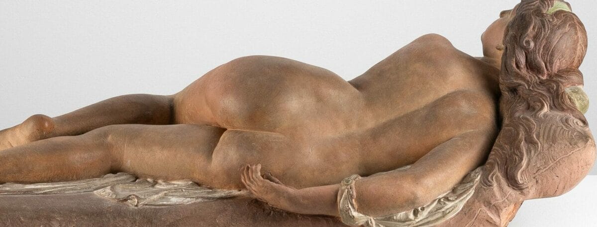 A polychrome terracotta statuette of a nude woman stretched out on a couch. Titled "The Vanity," it was sculpted and painted by Joseph Félon for the 1866 Salon.